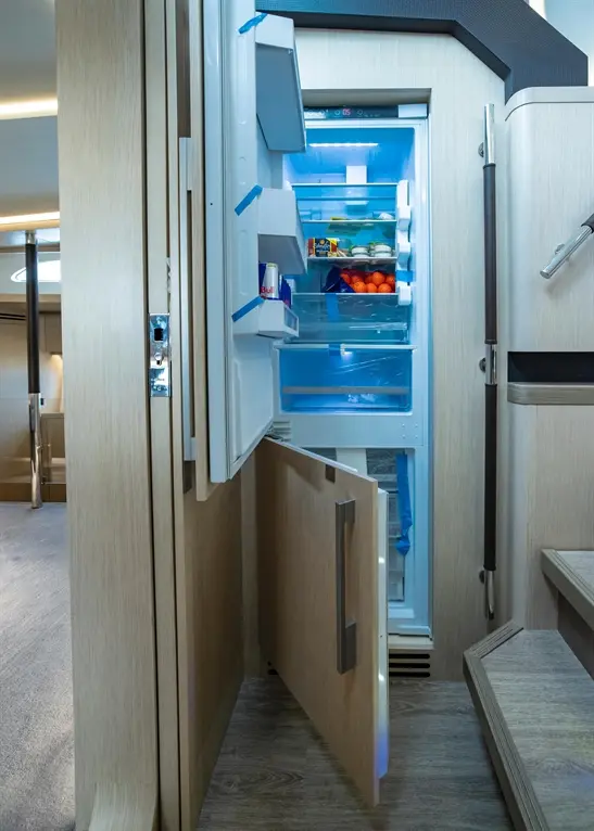 Modern kitchen featuring an open refrigerator with blue lighting, showcasing fruit, drinks, and shelving in a sleek design.
